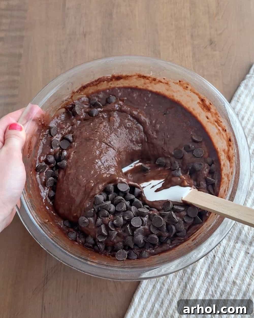 Stirring chocolate chips into the banana bread batter, ensuring melty pockets of goodness.