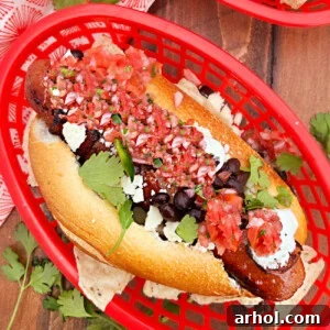 A delicious Sonoran hot dog with bacon, black beans, Cotija cheese, and salsa on a bolillo roll.