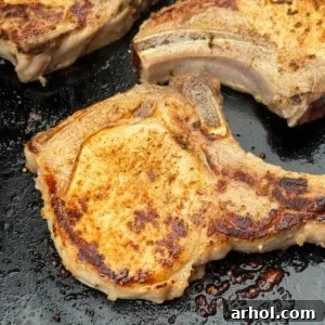Thick-cut, bone-in pork chops sizzling on a Blackstone griddle.