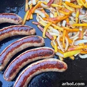 Sizzling Italian sausages with colorful peppers and onions on a Blackstone griddle.