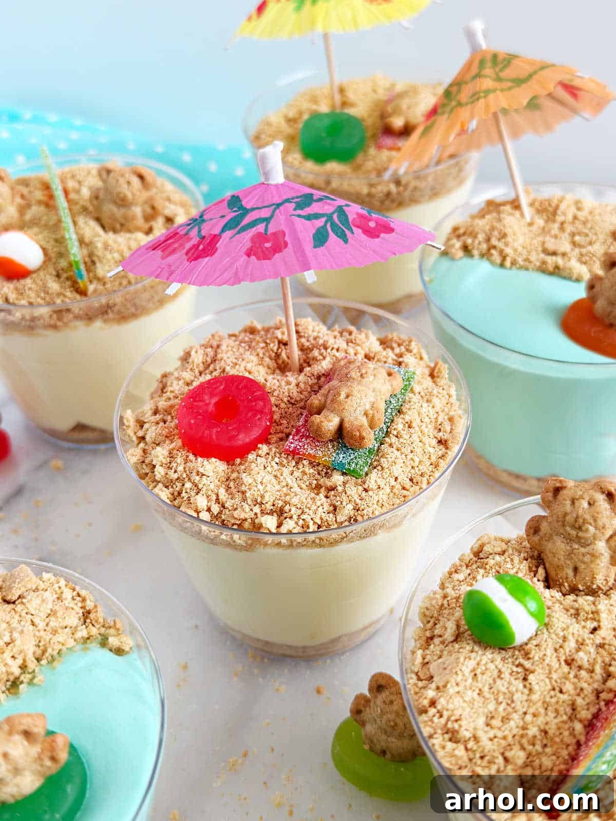 A finished beach pudding cup with a Teddy Graham sunbather on a candy towel, complete with a paper umbrella.