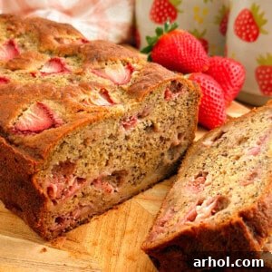 A loaf of strawberry banana bread on a cutting board
