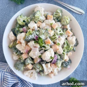 broccoli cauliflower salad with cheese in a creamy dressing in white serving bowl