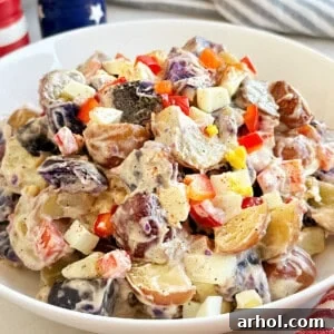 red, white and blue potato salad with red peppers in serving bowl.