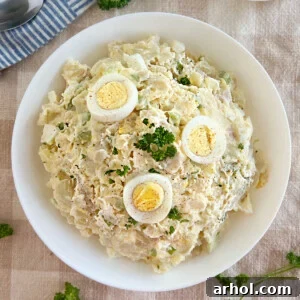 grandma's potato salad with red potatoes, eggs and parsley in a white serving bowl