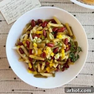 three bean salad in a white serving bowl with original recipe card.