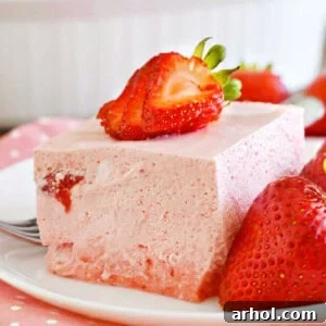 strawberry jello salad on a plate with strawberries.