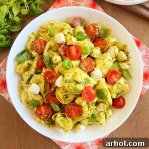 tortellini pasta salad with pesto sauce in white serving bowl.
