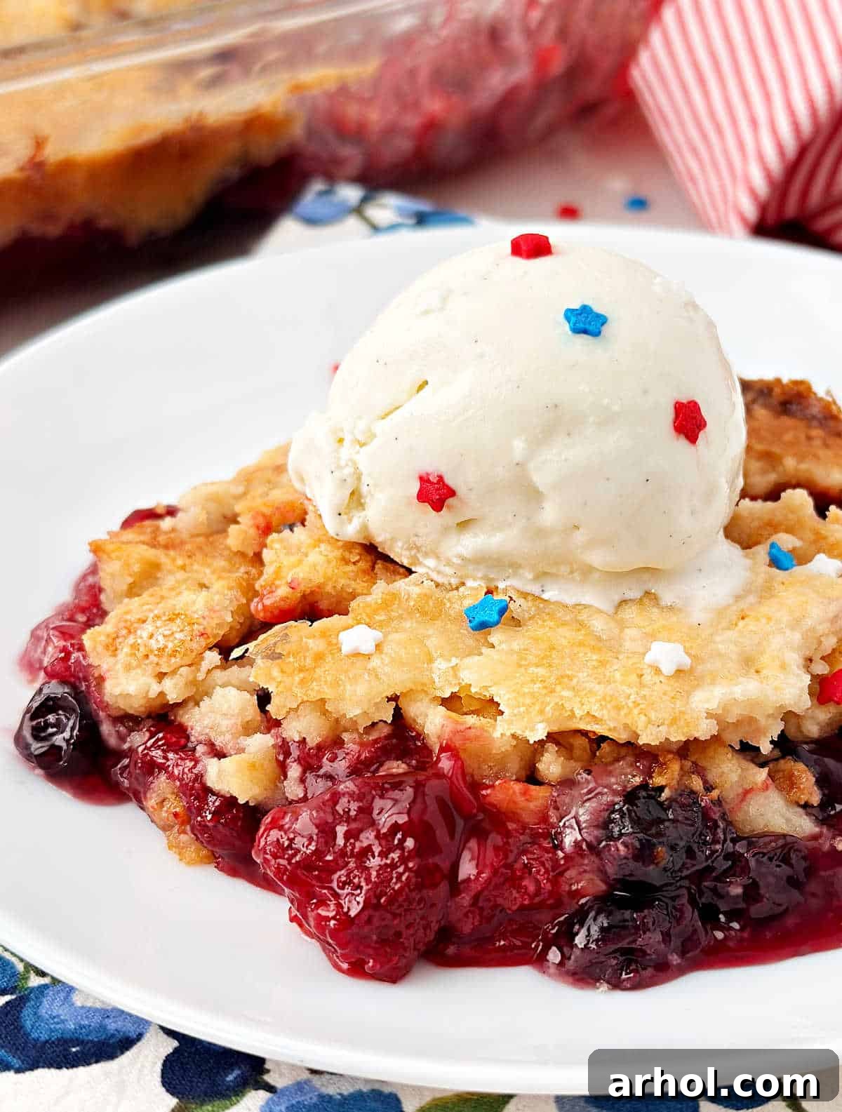 red white and blue dump cake with strawberries, blueberries and vanilla ice cream.