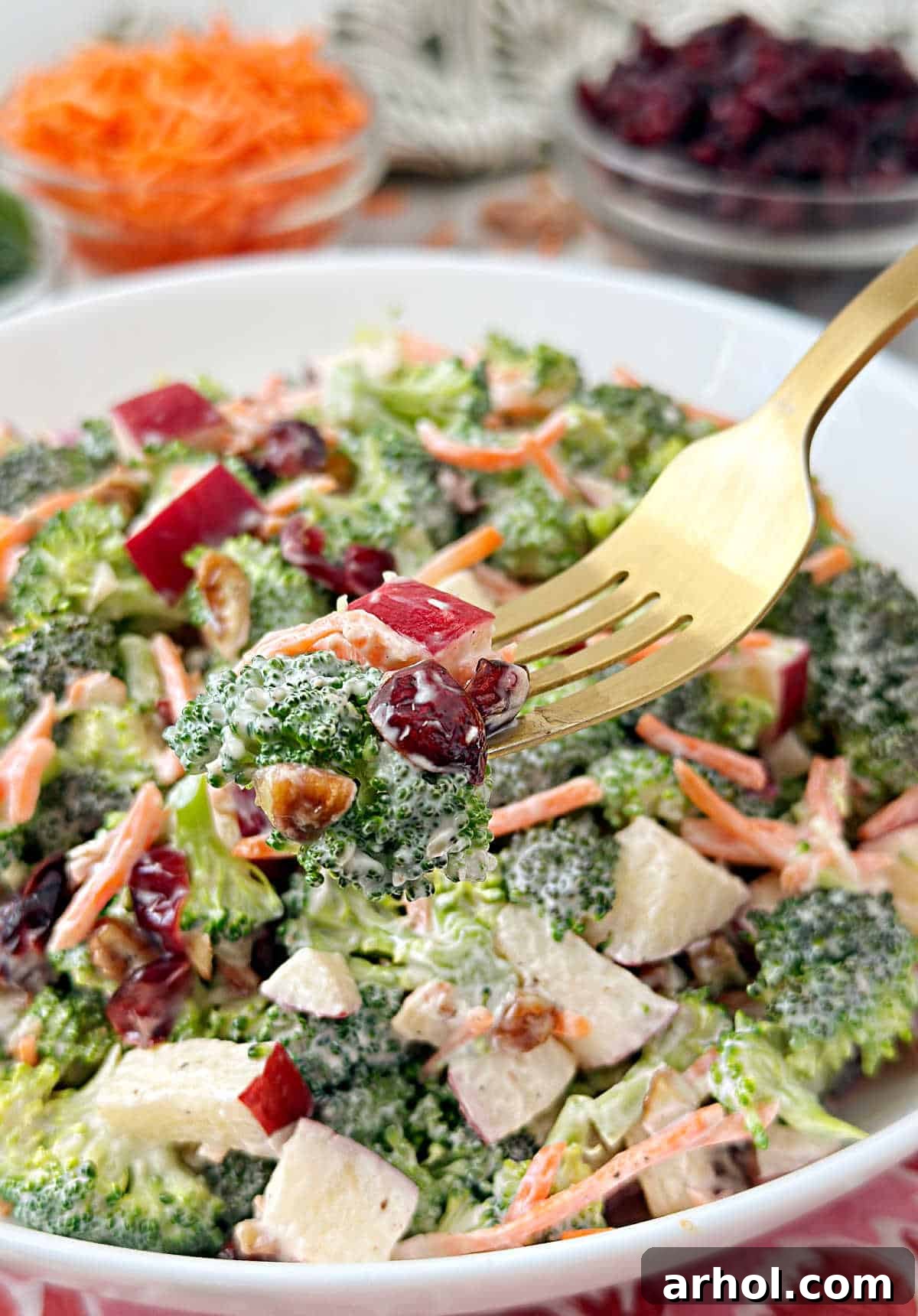 broccoli salad with craisins on a gold fork.