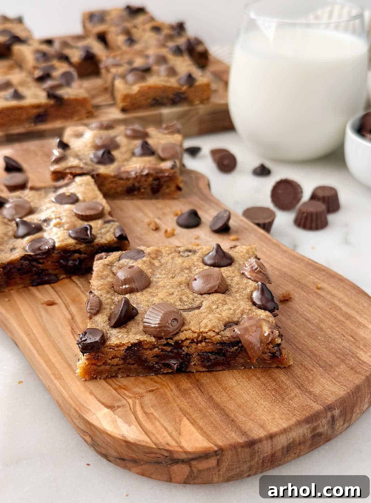 peanut butter chocolate chip bars with peanut butter cups on cutting board.