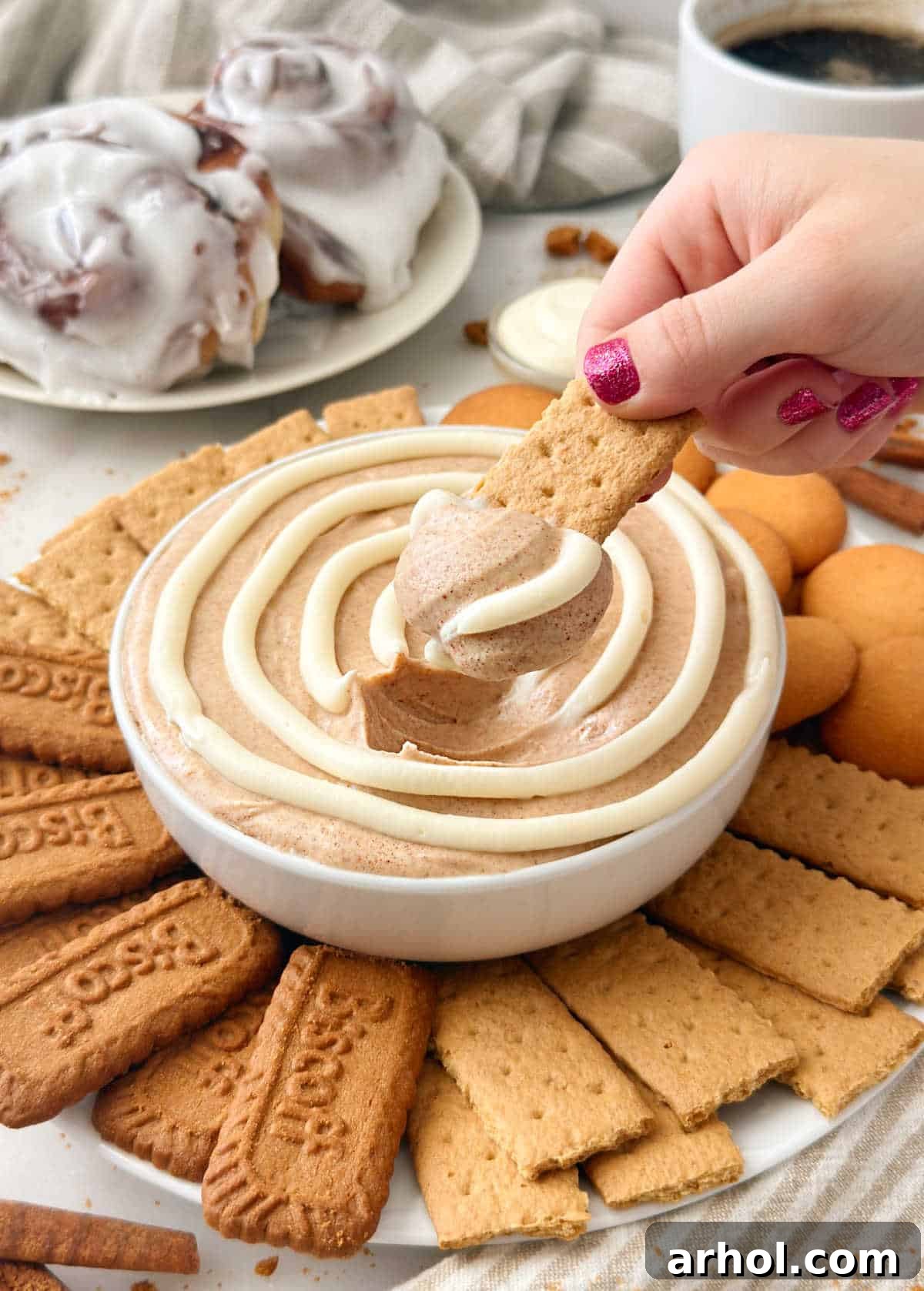 dipping graham cracker into cinnamon roll dip.