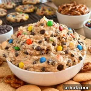 bowl of monster cookie dough dip with cookies and pretzels on the table.