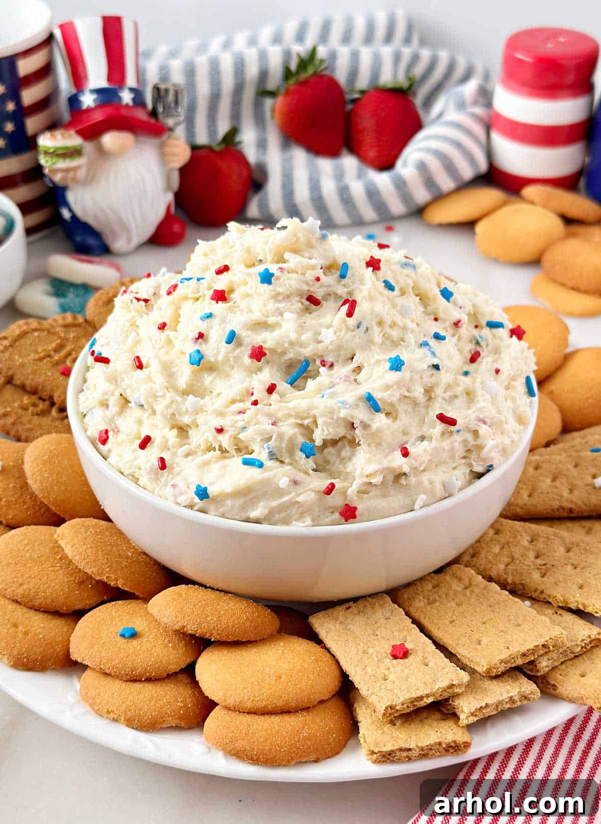 bowl of patriotic funfetti dip with red, white and blue sprinkles and dippers.