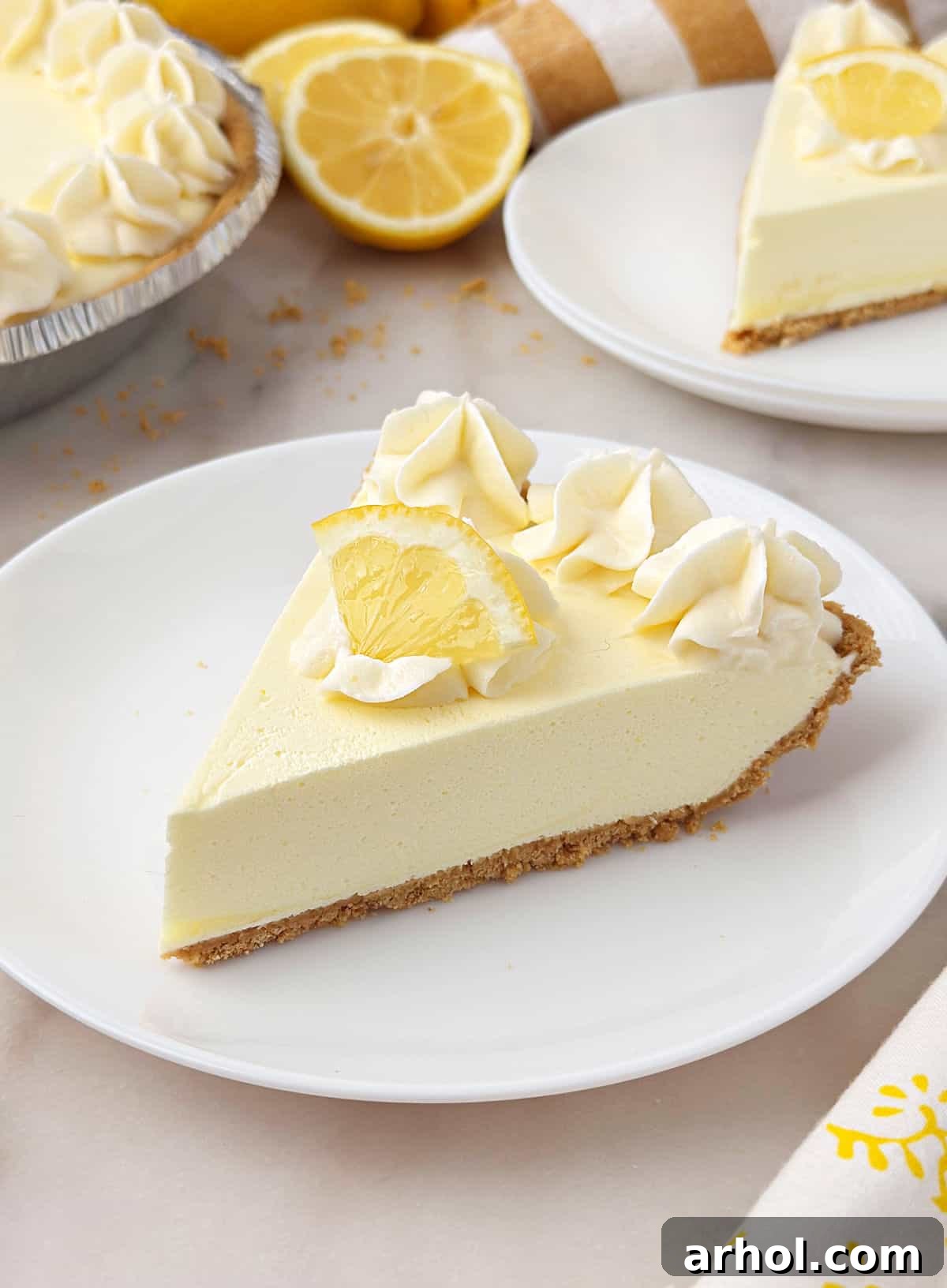 No-Bake Creamy Lemon Jello Pie 2 Slices of lemon jello pie on white plates with piped whipped cream.