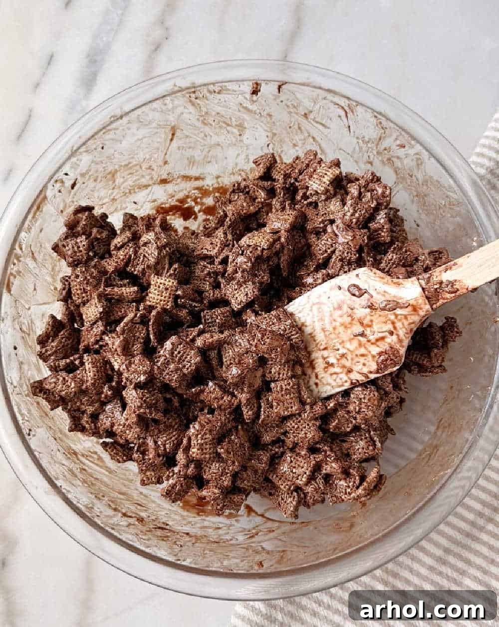 mixing chex cereal into chocolate with spatula.