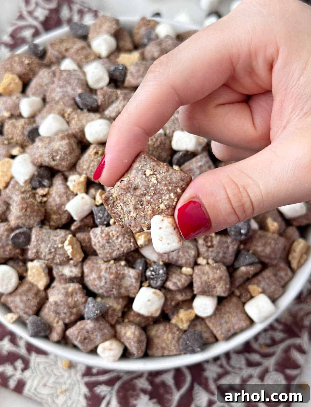 holding smores puppy chow in fingers.