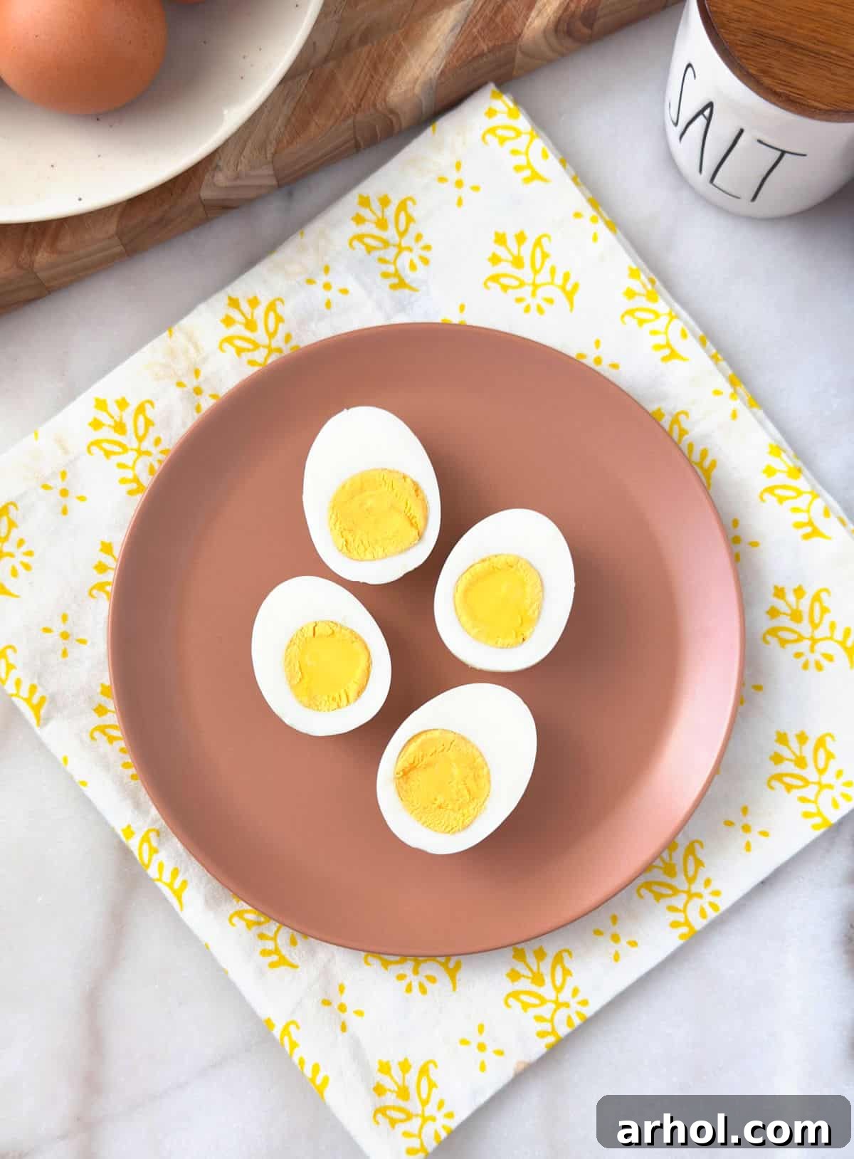 perfect hard boiled eggs with yellow yolks sliced in half on a plate.