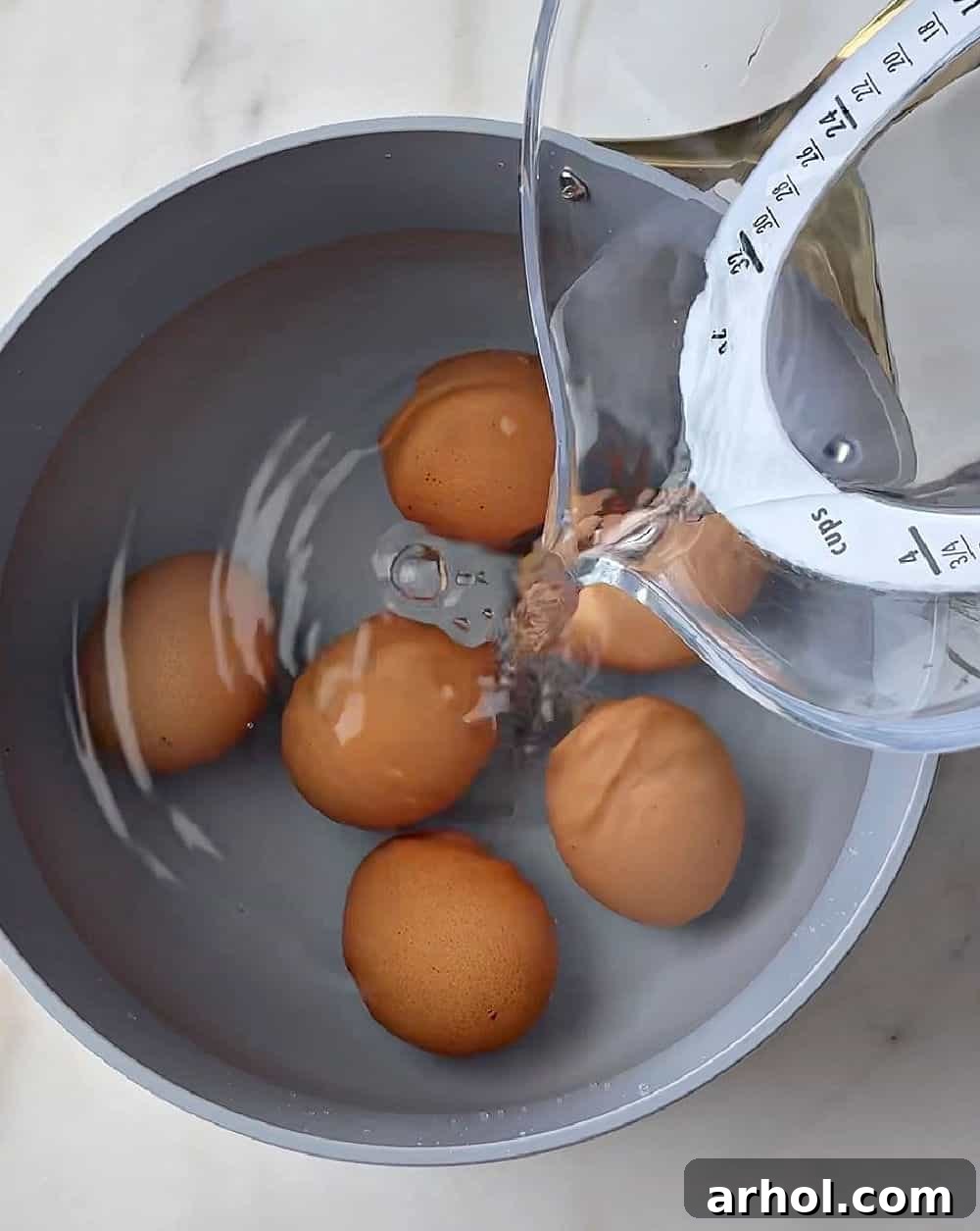 pouring water over eggs in pot.