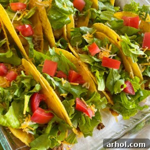 crispy oven baked tacos with ground beef, cheese, lettuce and tomatoes in baking dish