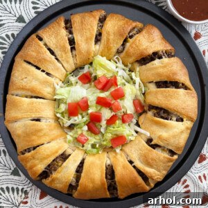 baked taco ring made with crescent rolls with shredded lettuce and tomatoes inside.