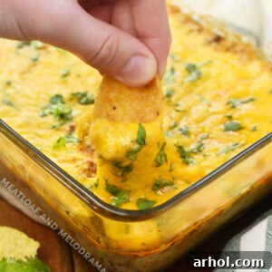 Dip frito chip into baked taco dip recipe with ground beef, cream cheese and cheese