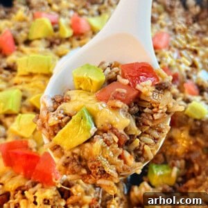taco rice with ground beef and cheese in a serving spoon.