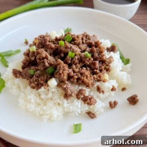 Korean ground beef with green onions over rice on a plate.