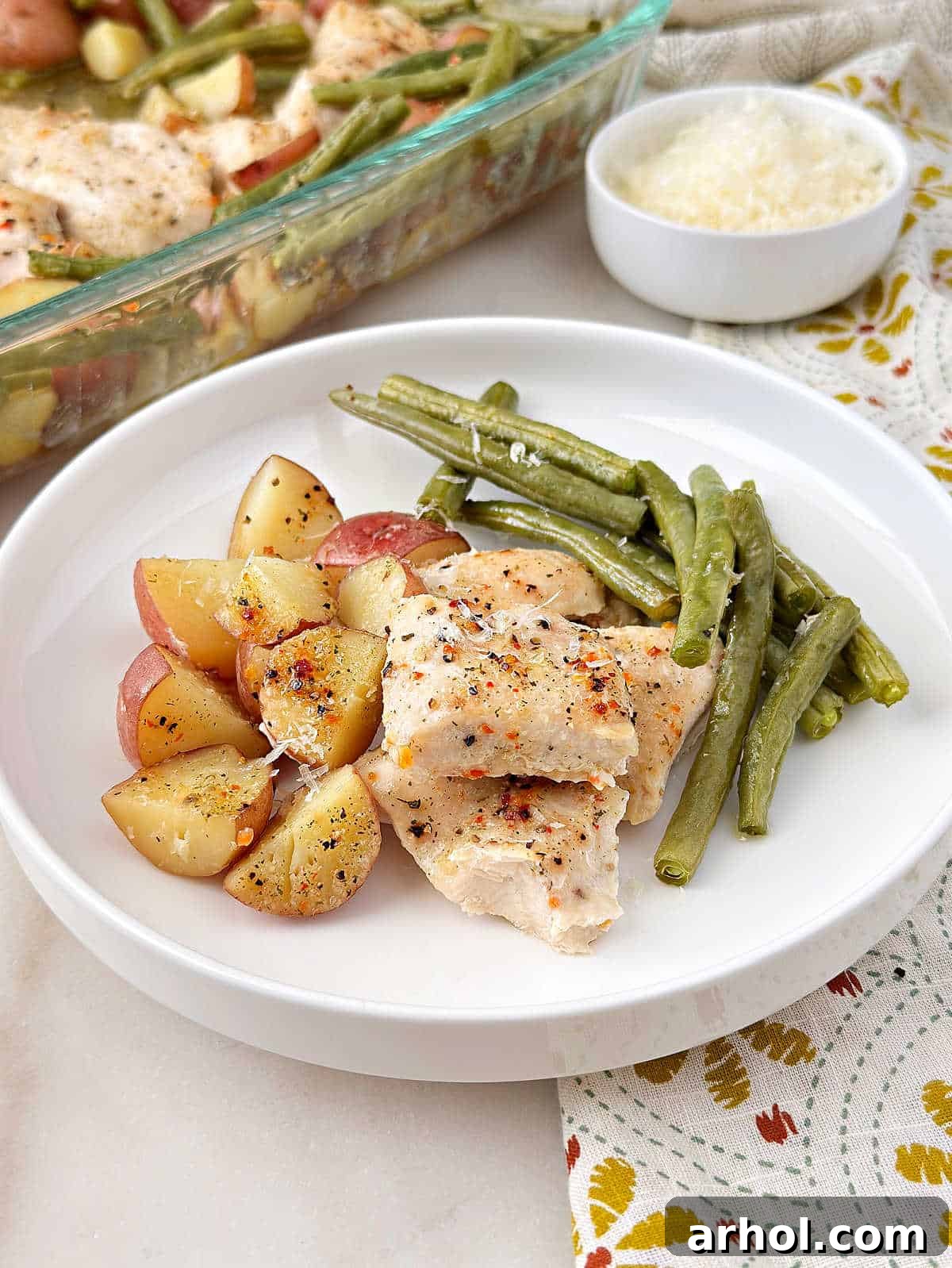 Italian chicken, green beans and red potatoes on a white dish.