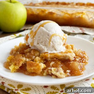 caramel apple dump cake with scoop of vanilla ice cream and caramel sauce on plate.