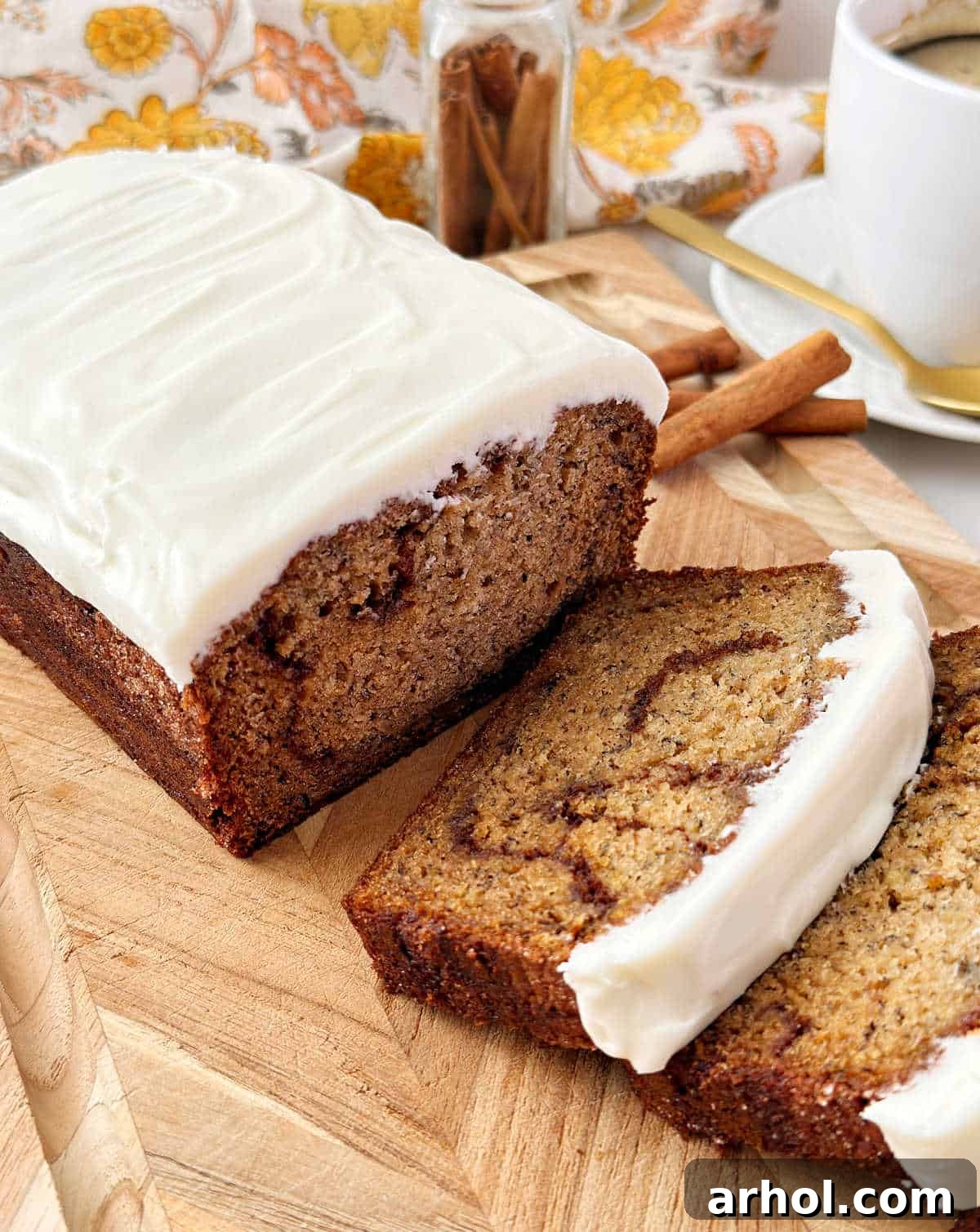 cinnamon roll banana bread with sweet cream cheese frosting on cutting board.
