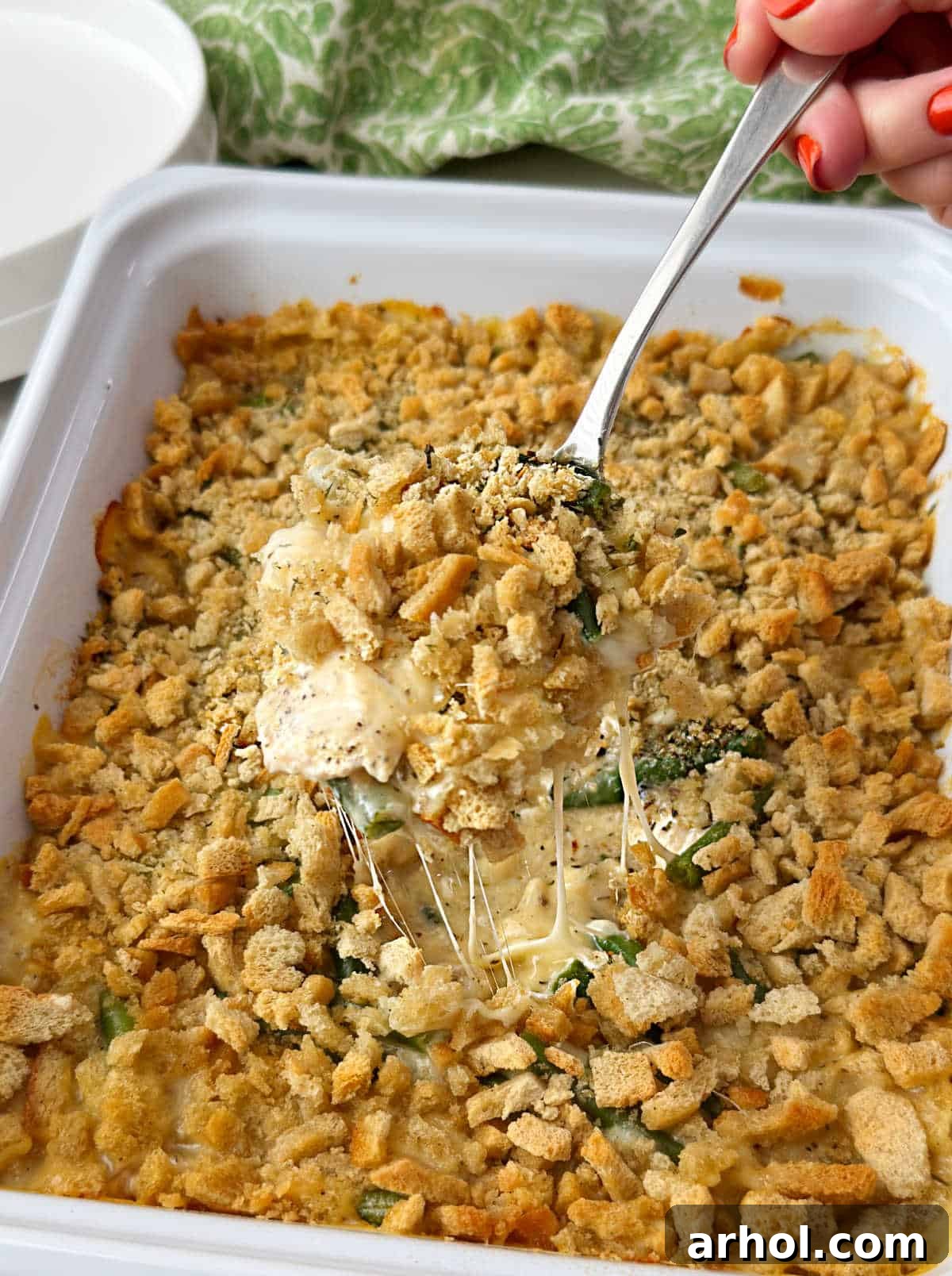 Swiss chicken casserole with stuffing and green beans on serving spoon.