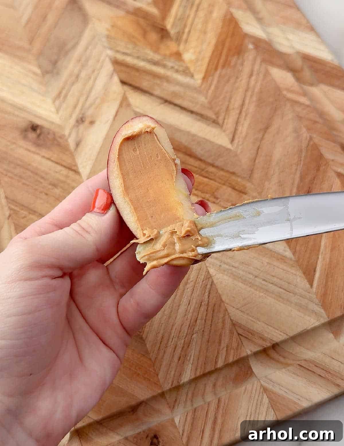 spreading peanut butter on apple slice.