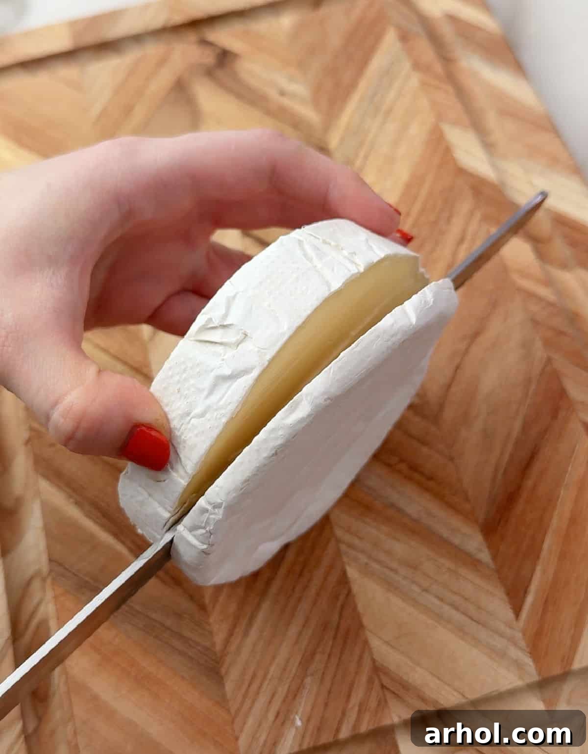 slicing top off wheel of Brie cheese.